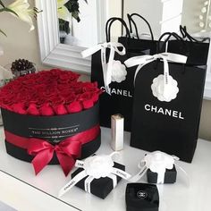 two black and white bags with red roses in them on a table next to a mirror