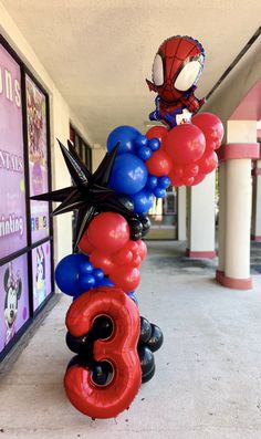 balloons are arranged in the shape of numbers and spider - man faces on display outside an office building