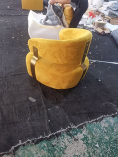 a yellow chair sitting on top of a black floor next to a pile of furniture