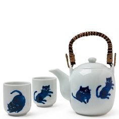 a white tea pot with blue cats painted on it and two cups next to it