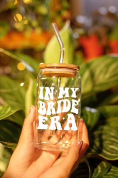 a hand holding a mason jar with the words in my bride era on it