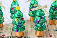 green plastic christmas trees with buttons and bows on them are sitting on a wooden table