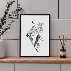 a black and white art print on a shelf next to a vase with flowers in it