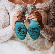 a bride holding two wedding shoes with the words happily ever after written on them