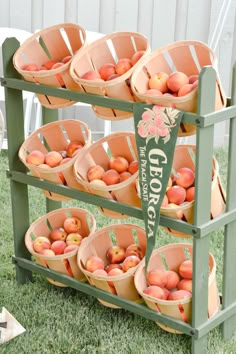 an outdoor fruit stand with peaches and apples in buckets on the top shelf