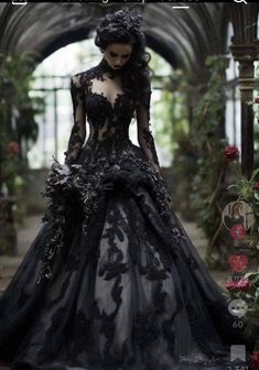 a woman in a black and white dress with flowers on her head is standing near an archway