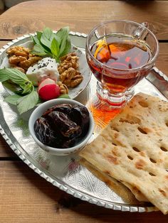 a silver plate topped with food next to a cup of tea