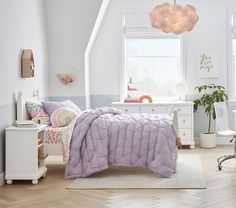 a bed room with a neatly made bed next to a window and a table in front of it