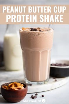 peanut butter cup protein shake in a glass with chocolate chips on the side and milk behind it