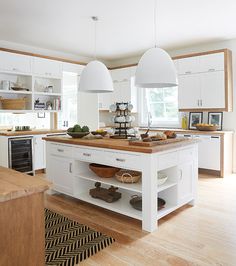 a large kitchen with white cabinets and wooden counter tops, along with an island in the middle