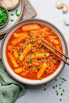 a bowl of noodles and carrots with chopsticks