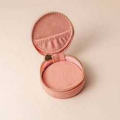 an open pink velvet jewelry box on a white surface