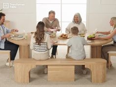 a group of people sitting around a wooden table eating food and drinking water from cups