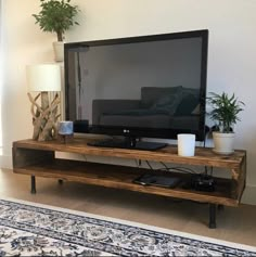 a flat screen tv sitting on top of a wooden stand in a living room next to a window