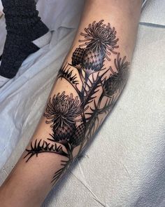 a black and white tattoo on the arm of a person with flowers in it,