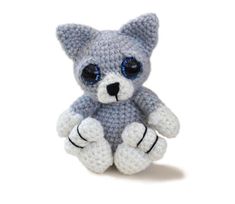 a small crocheted stuffed animal sitting on top of a white surface with blue eyes