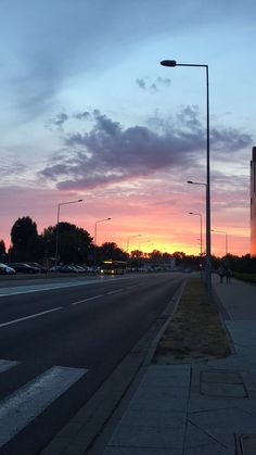 the sun is setting over an empty street