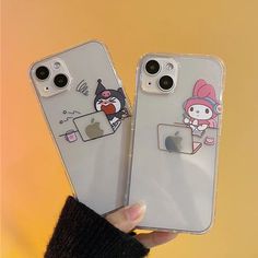 two clear cases with stickers on them are held up in someone's hand