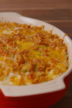 a red casserole dish with cheese and meat in it on a wooden table