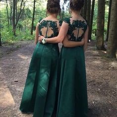 two women standing in the woods looking at each other with their back to the camera