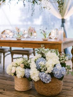 two baskets filled with flowers sitting on top of a wooden floor next to a table