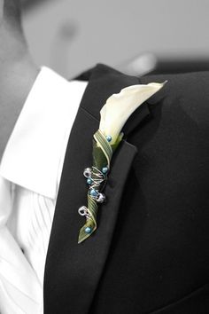 a man wearing a black suit with a white flower on it's lapel