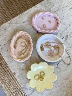 three decorative items sitting on top of a marble table next to a bowl and ring dish