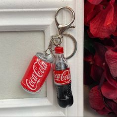 two coca - cola cans are attached to a keychain on a white door