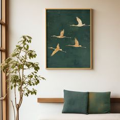 a painting hanging on the wall above a couch with pillows and a potted plant