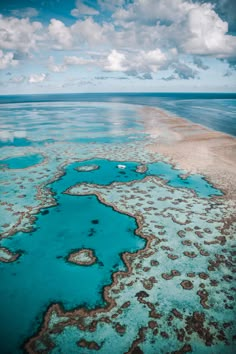 an aerial view of the great barrier reef in the middle of the ocean with blue water and clouds