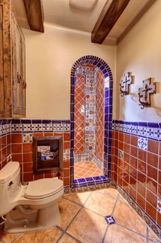 a bathroom with a toilet, sink and tiled walls