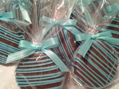 four chocolate covered strawberries wrapped in cellophane and tied with blue ribbon, on a table