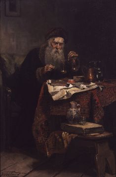 an old man sitting at a table in front of a book and some other items