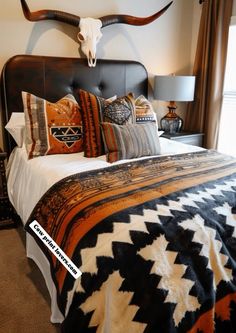 a bed room with a neatly made bed and a cow skull mounted on the wall