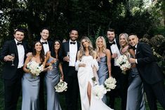 a group of people standing next to each other in formal wear posing for a photo