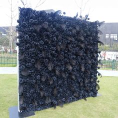 a large black piece of art sitting on top of a green grass covered park area