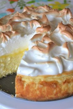 a lemon meringue pie on a plate with one slice cut out and ready to be eaten