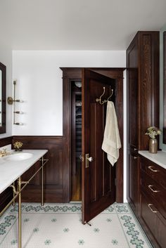 a bathroom with wooden cabinets and marble counter tops, along with a white rug on the floor