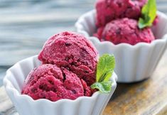 three scoops of raspberry ice cream on a wooden tray