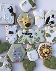 baby shower cookies decorated like animals, giraffes and zebras with welcome to the jungle written on them