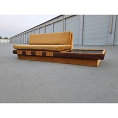 two couches sitting on top of each other in front of a warehouse building with roller doors