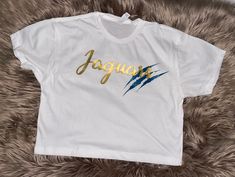 Get ready to roar with style in our Jacksonville Jaguars Crop Top! Also available as a T-shirt. Show off your team pride with this sassy and sporty top that's perfect for game days, tailgates, or just strutting your stuff with Jaguars spirit. The sleek design and vibrant team colors make it a touchdown for fashion-forward fans. Crafted for comfort and flair, this crop top is a must-have for every Jag! Available in gray, black, and white.  Message me for any questions! Jaguar Outfit, Jax Jaguars, Jacksonville Jaguars Outfit, Jaguar T Shirt Design, Jacksonville Jaguars Cheerleaders, Jacksonville Jaguars Shirt, Jacksonville Jaguars, Team Colors, Sleek Design