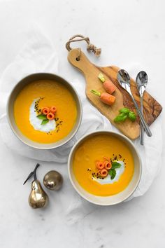 two bowls of carrot soup with cream and garnish