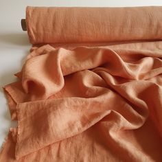 an orange cloth is laying on top of a white surface and the fabric has been folded