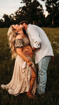 a man and woman kissing in the grass