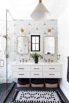 a bathroom with two sinks, mirrors and rugs in front of the shower area