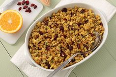 a white dish filled with cranberry stuffing next to an orange slice and spoon