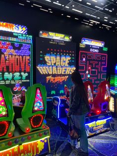 a woman standing in front of several video game machines with neon lights on the sides