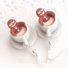 two cupcakes with faces on them are hanging from silver earwires,