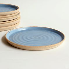 a stack of blue plates sitting on top of a white table next to each other